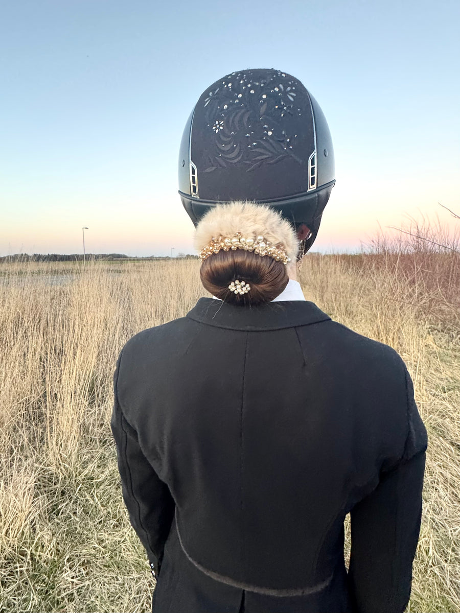 Rider seen from behind with a fur-and-pearl BelliNoxx bun under an embroidered helmet